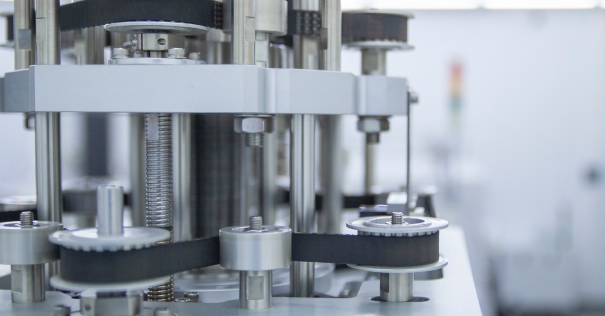 A block of servo motors connected to an industrial machine with belts. The machine is in an electronic equipment factory.
