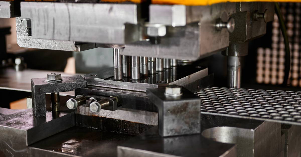 A metal stamping machine in the process of cutting circular steel blanks from a long metal strip.