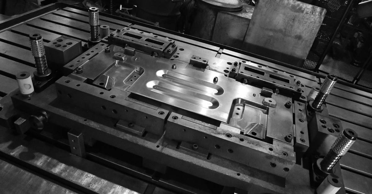 A sheet metal stamping tool die for precision automotive parts on a numerical control milling machine table.