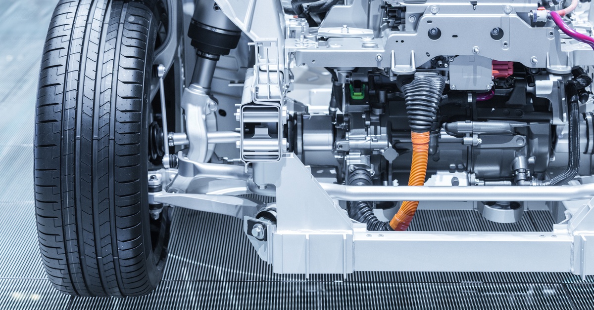 A close-up look at the electrical workings of a stripped vehicle and the metal framework; there’s one wheel attached.