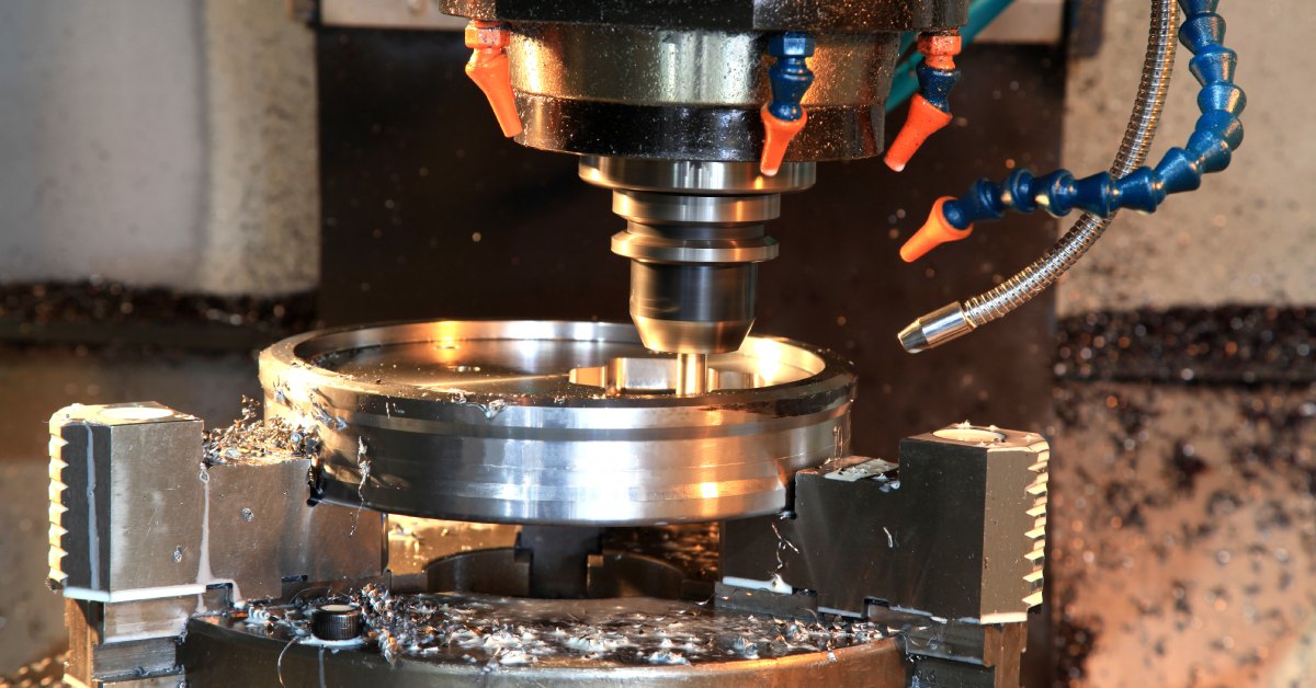 A die tool with the die inside of a shallow silver cylinder. Threads of silver are on the base of the machine.