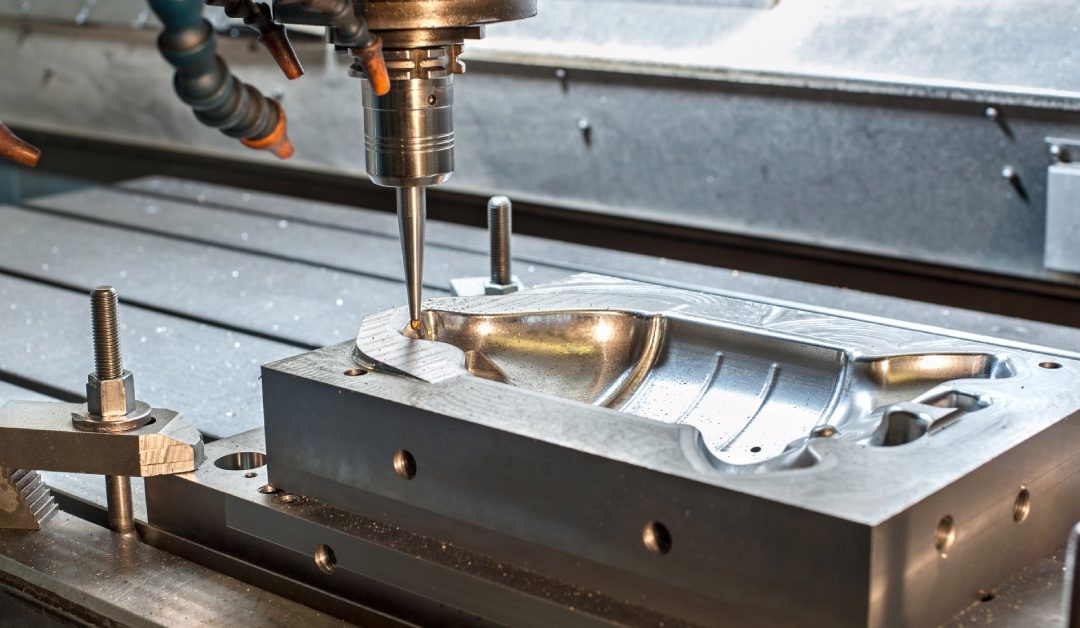 A large piece of silver laying on a work bench beneath a die machine. The die is just above the metal form.
